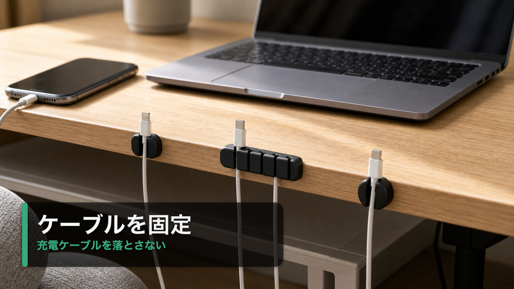 ケーブルホルダーで充電ケーブルの先端を机の端に固定したデスク風景